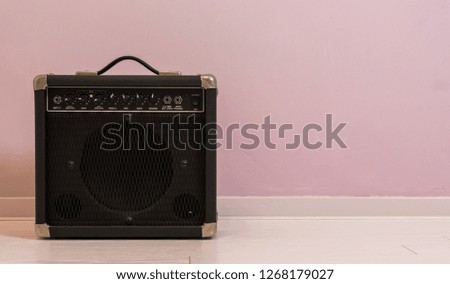 portable electric guitar amplifier isolated in front of a stone wall, music equipment background