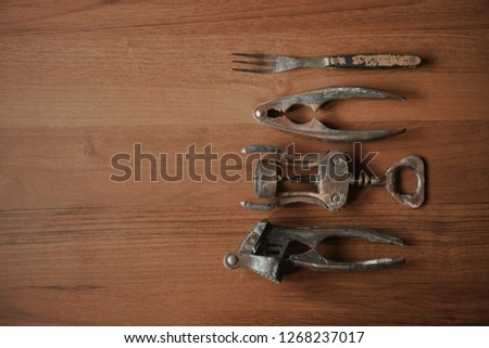 Heap of Kitchen Tools with Corkscrew, Garlic Press, fork, Nutcracker on wooden table background . empty copy space