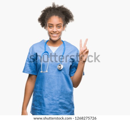 Young afro american doctor woman over isolated background showing and pointing up with fingers number two while smiling confident and happy.