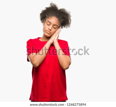 Young afro american woman over isolated background sleeping tired dreaming and posing with hands together while smiling with closed eyes.
