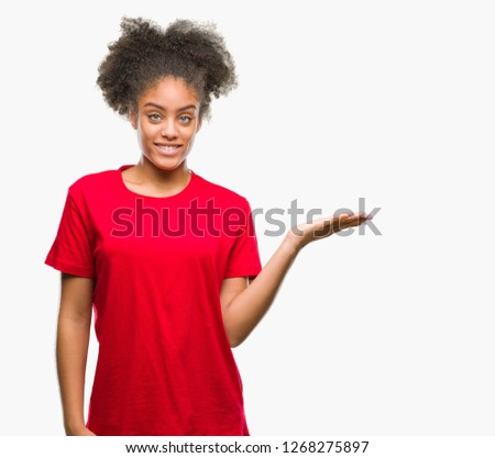 Young afro american woman over isolated background smiling cheerful presenting and pointing with palm of hand looking at the camera.