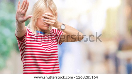 Young beautiful blonde woman over isolated background covering eyes with hands and doing stop gesture with sad and fear expression. Embarrassed and negative concept.