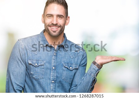 Young handsome man over isolated background smiling cheerful presenting and pointing with palm of hand looking at the camera.