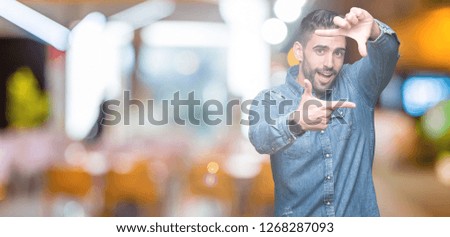 Young handsome man over isolated background smiling making frame with hands and fingers with happy face. Creativity and photography concept.