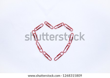 Paper clips laid out in the shape of a heart on a white background. Valentine's Day celebration concept in minimal style.