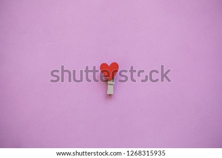 Clothespin with a heart on a pink background in a minimal style.