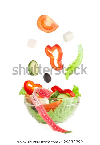 Picture of falling fresh vegetables in plate with greek salad and tape-measure