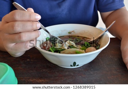 Thai style pork noodles in spicy curry, a famous Thai cuisine consited of different ingredients as preferred by the restaurant, in the picture, meatballs, noodle, pork mixed together in rich pork soup