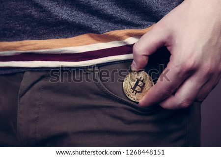 Putting bitcoin cryptocurrency coin into the pocket 