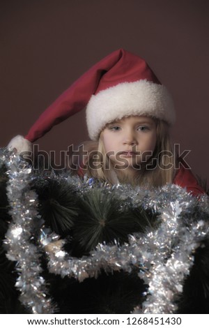 little girl blonde in christmas hat with garland