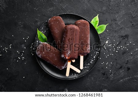 Chocolate ice cream on a stick. On a black background. Top view. Free copy space. Royalty-Free Stock Photo #1268461981