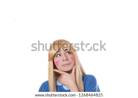 Cute young girl in star cosplay with hearts on cheeks thinking isolated 