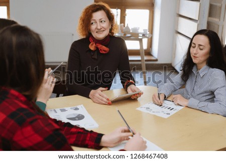 Group of woman consulting with editor during informal meeting in cafe asking questions and explaining concept of work using laptop and wireless connection