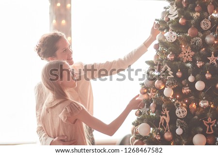 happy mom and little daughter decorating the Christmas tree