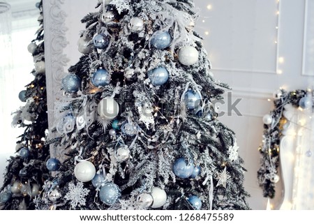 Close up photo of Christmas decor with white and blue color of a bright stylish living room with gifts, fireplace, Christmas tree and candles