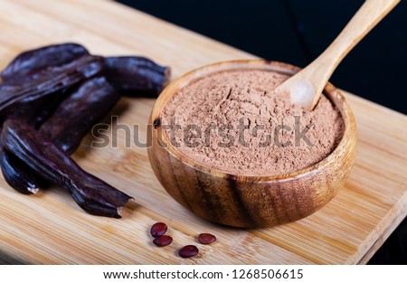 Carob pods and carob powder over wooden background  Royalty-Free Stock Photo #1268506615