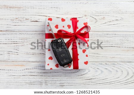 Valentine or other holiday handmade present in paper with red hearts, car keys and gifts box in holiday wrapper. box gift on white wooden table top view with copy space, empty space for design.
