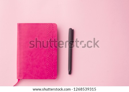 Pink diary, pen top view on a pink background. Selective focus
