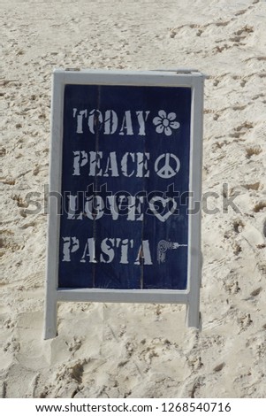Cute Chalkboard Restaurant Sign Advertising "Peace, Love, and Pasta" on a Sandy Beach
