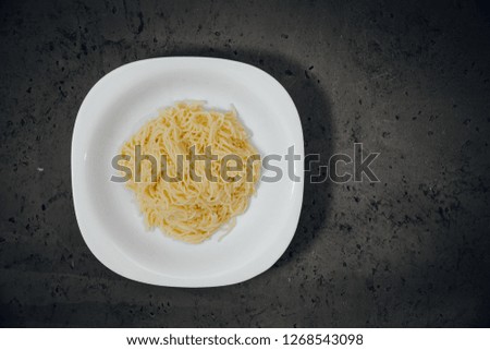 Top view on a white plate with pasta on a dark, stone counter top. Dough poured into a plate. Food concept.