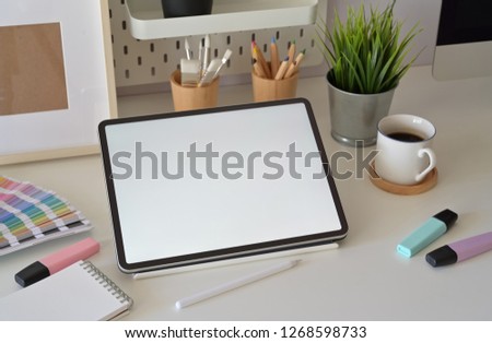 Blank screen tablet on desktop in graphic design studio