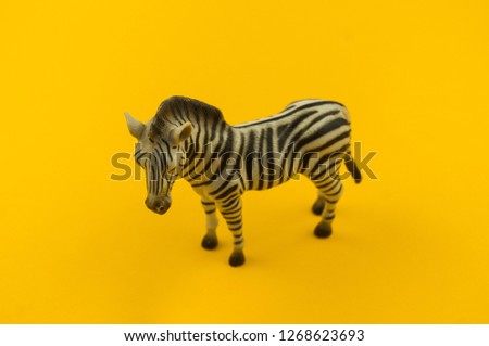 Toy zebra from plastic on a yellow background. African animal for a child. Place to write.