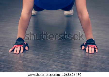 Young woman practicing yoga, doing Push ups or press ups exercise, phalankasana Plank pose, working out, wearing sportswear, indoor, home interior, living room floor. Close-up of hands.