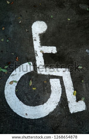 white wheelchair  sign for disability on concrete floor