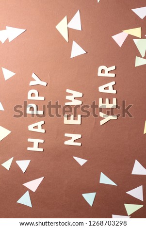 Happy New Year conceptual picture. Brown background. Wooden alphabets. Confetti.