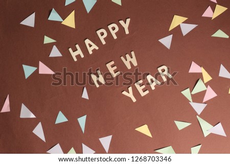 Happy New Year conceptual picture. Brown background. Wooden alphabets. Confetti.