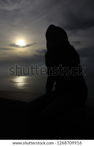 Silhouette of a girl wearing hijab sitting.