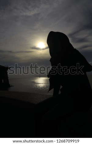 Silhouette of a girl wearing hijab sitting.