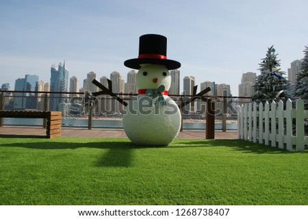 snowman and Christmas tree on Dubai background. On blurred background skyscrapers and Dubai beach