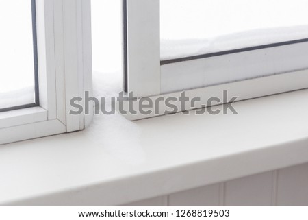 Snow on the windowsill between unscrewed shutters