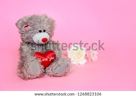 gray teddy bear with flowers on pink background for Valentine's Day