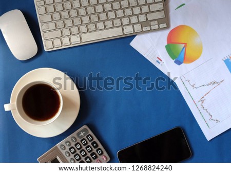  top view and modern blue desk work table with a  report graph chart, ,calculator ,keyboard,cup coffee