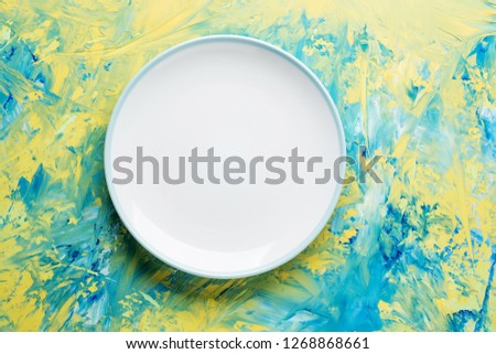 Empty ceramic round plate on colorful background with copy space.