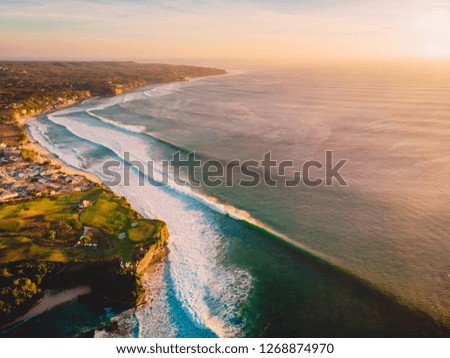Aerial shooting of waves in ocean and shore at sunset.