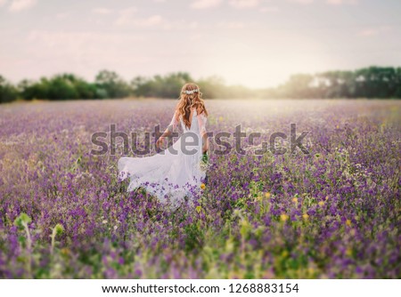 fantasy woman bride elegant long vintage white dress gown. hairstyle blond hair decorated white wreath, walks bloom field meadow purple flowers grass. Happy escaped run princess. sunset sun light