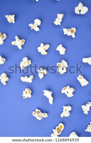 Popcorn lies evenly distributed on a colored surface - concept with a background consisting of popcorn which lies at a certain distance from each other on the surface