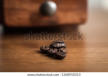 Coffee beans with coffee grinder in the background. Still life picture with small aperture