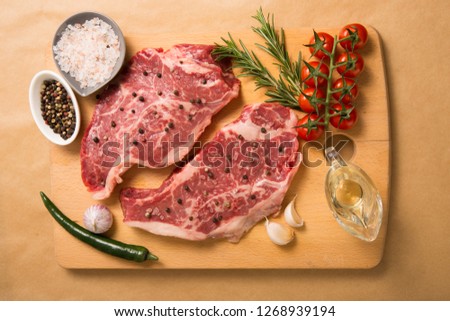 Raw marble meat with spices, rosemary on a wooden Board.