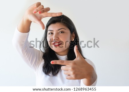 Smiling romantic girl making frame with hands and fingers. Young mix raced woman having fun, gesturing and posing. Picturing concept