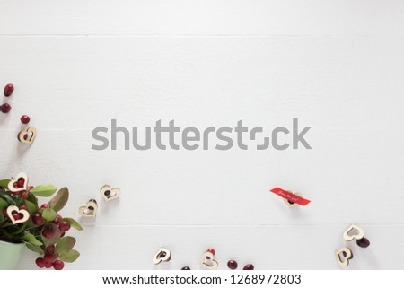 Festive white wooden background with many hearts, fresh red berries and little sign JUST FOR YOU. 