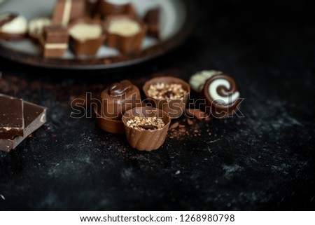 different, sweet pralines of dark, milk and white chocolate on a dark, wooden background