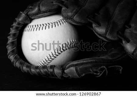 Baseball - This is a high contrast black and white photo of an old baseball inside of an old baseball glove.