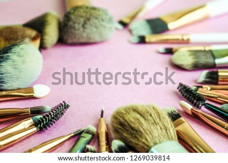 A frame from a set of beautiful different soft makeup brushes from natural lint for targeting beauty and applying a tonal base in a stand and copy space on a pink, purple background.