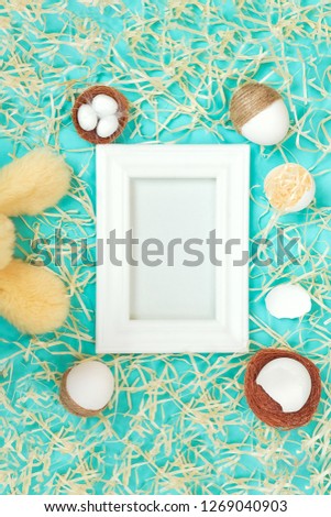 white Easter frame on a blue background with wood chips  Easter eggs and ears of the Easter Bunny