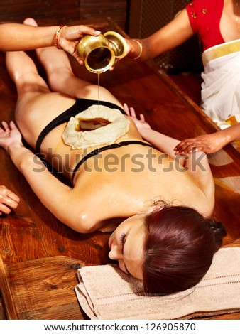Woman having oil Ayurveda spa treatment of back pain.