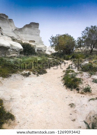 Rock cliffs by sand Milos island Greece